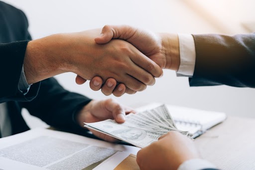 business handshake with money exchange