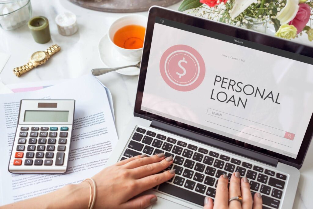 person applying for loan on laptop with calculator nearby