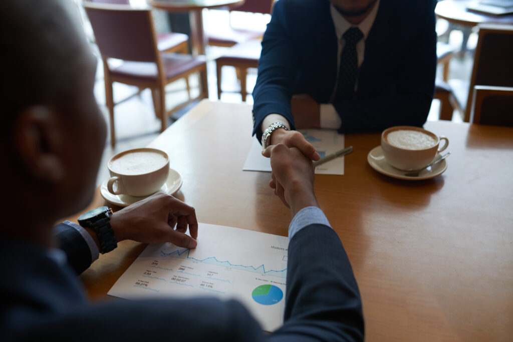business people shaking hands in cafe