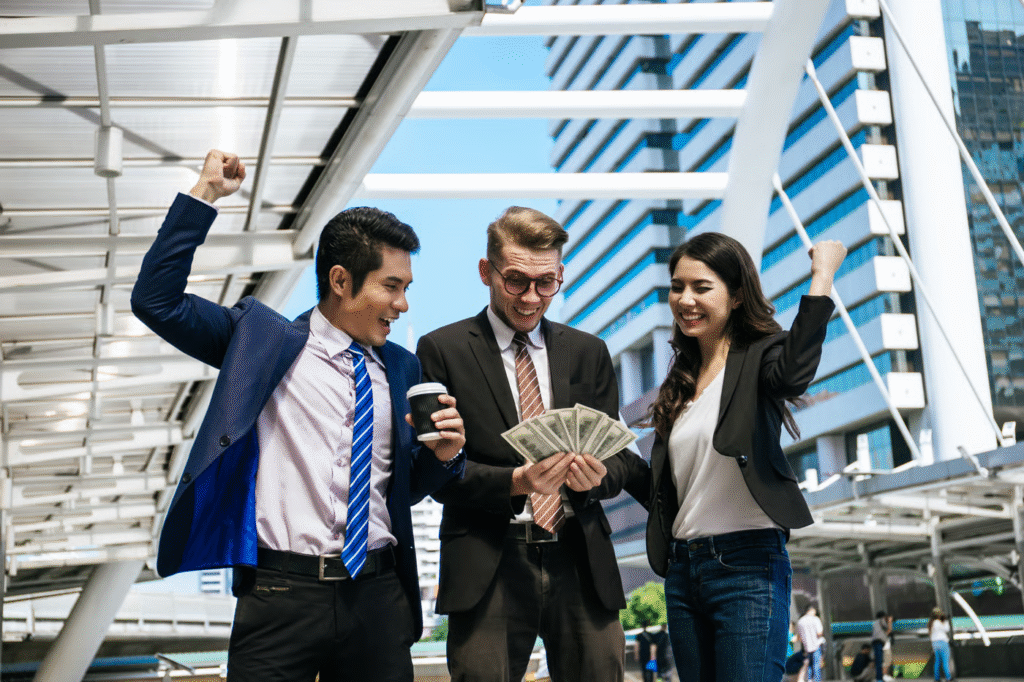Three People Celebrating with Money in City Setting