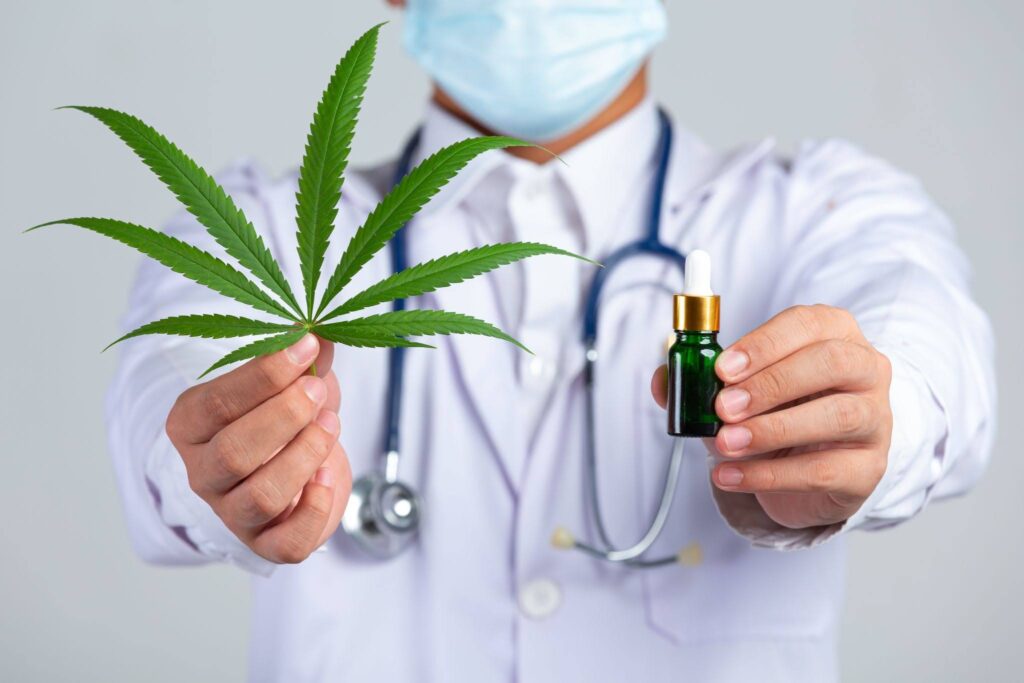 Medical doctor holding cannabis leaf and bottle of cannabis oil