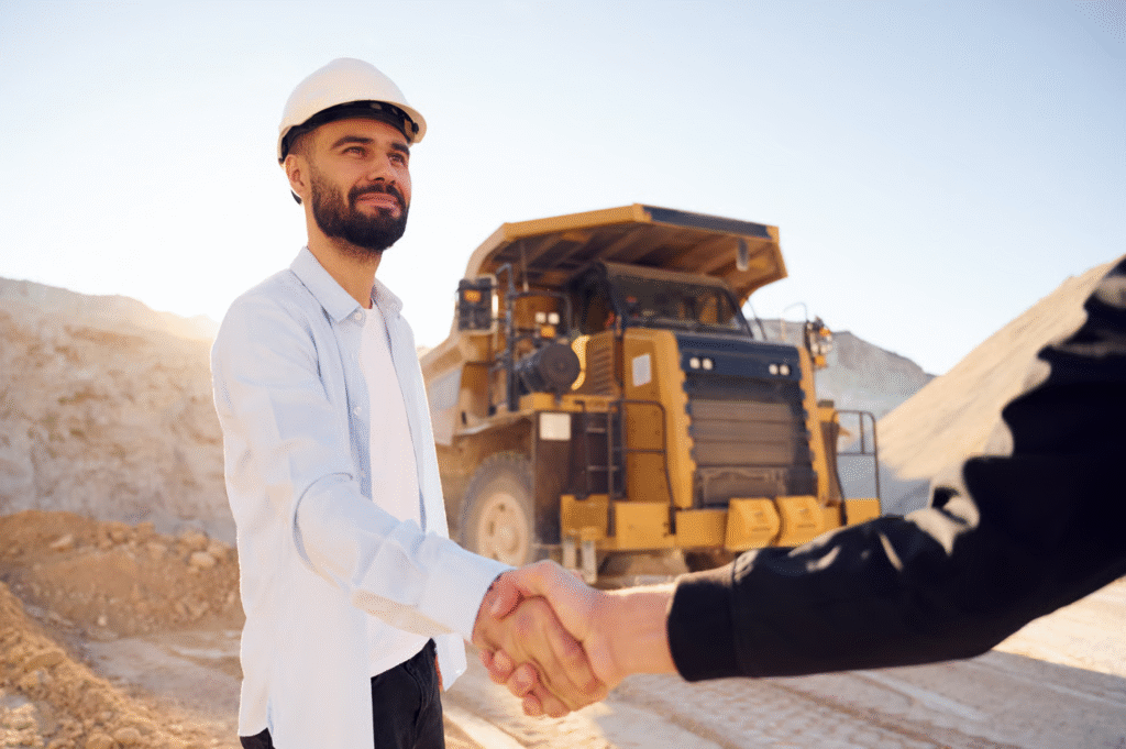 Construction Workers Shaking Hands Near Heavy Machinery