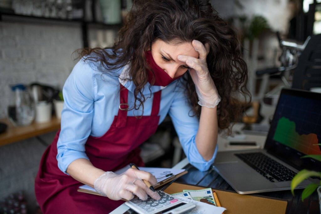 Frustrated coffee shop manager calculating figures in cafe