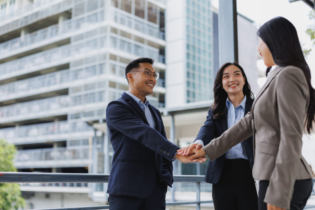 Business team joining hands in modern city, showing unity and collaboration