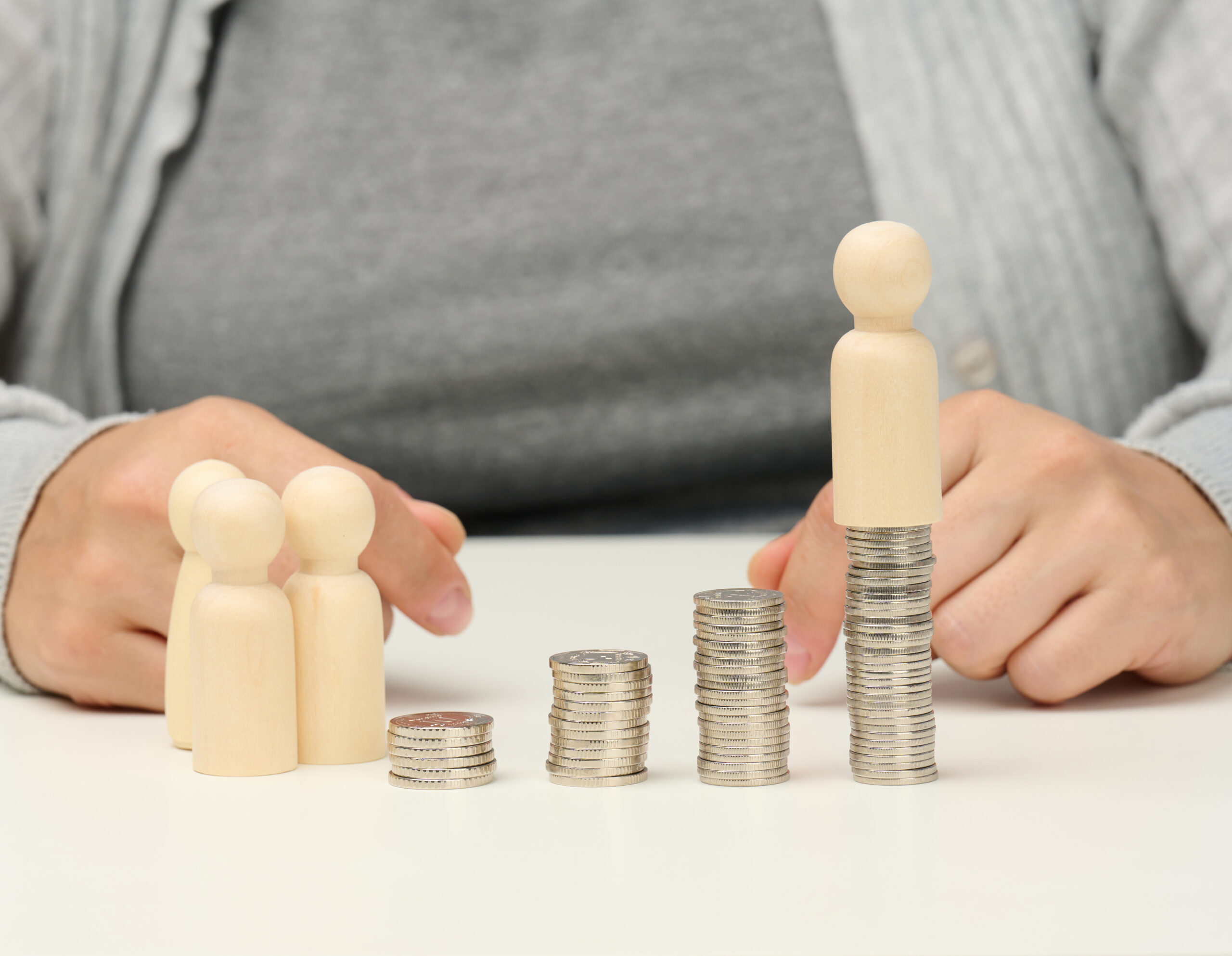 stack of metal coins and wooden figures of men on a white table. Savings and expenses, family budget, subsidies from the state