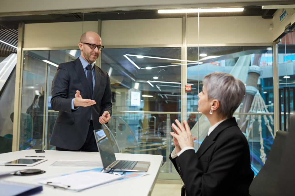 Portrait of smiling bald businessman greeting female colleague in meeting room, copy space
