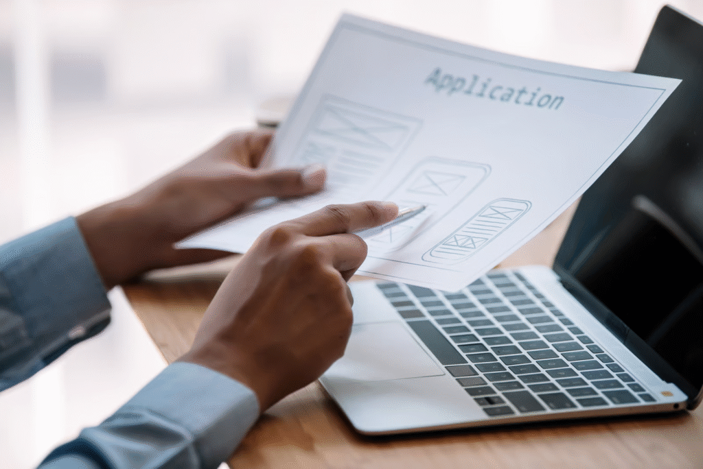 Person Holding Application Document Near Laptop Computer