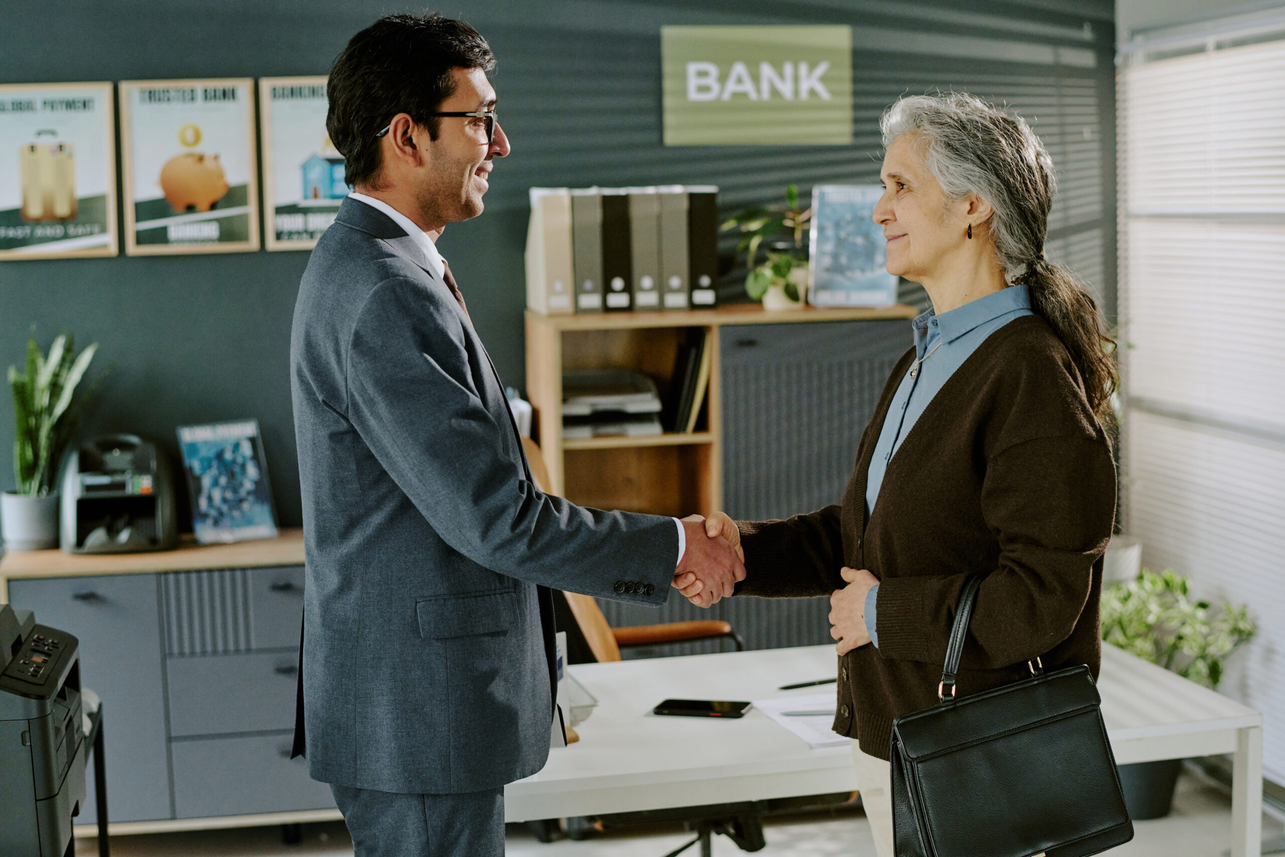 Businessman Shaking Hands with Elderly Hispanic Woman in Office