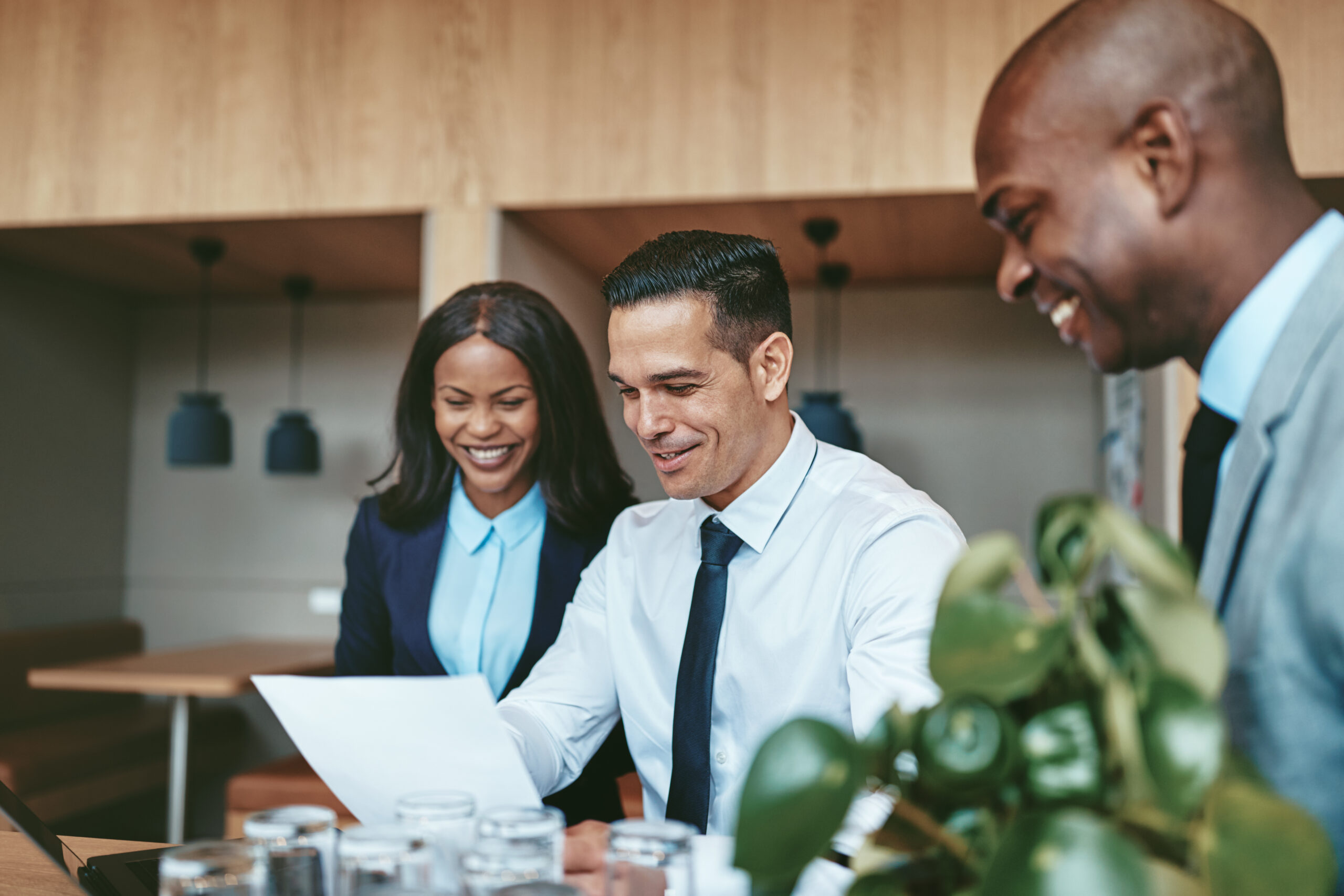 Three diverse businesspeople laughing while going over documents together