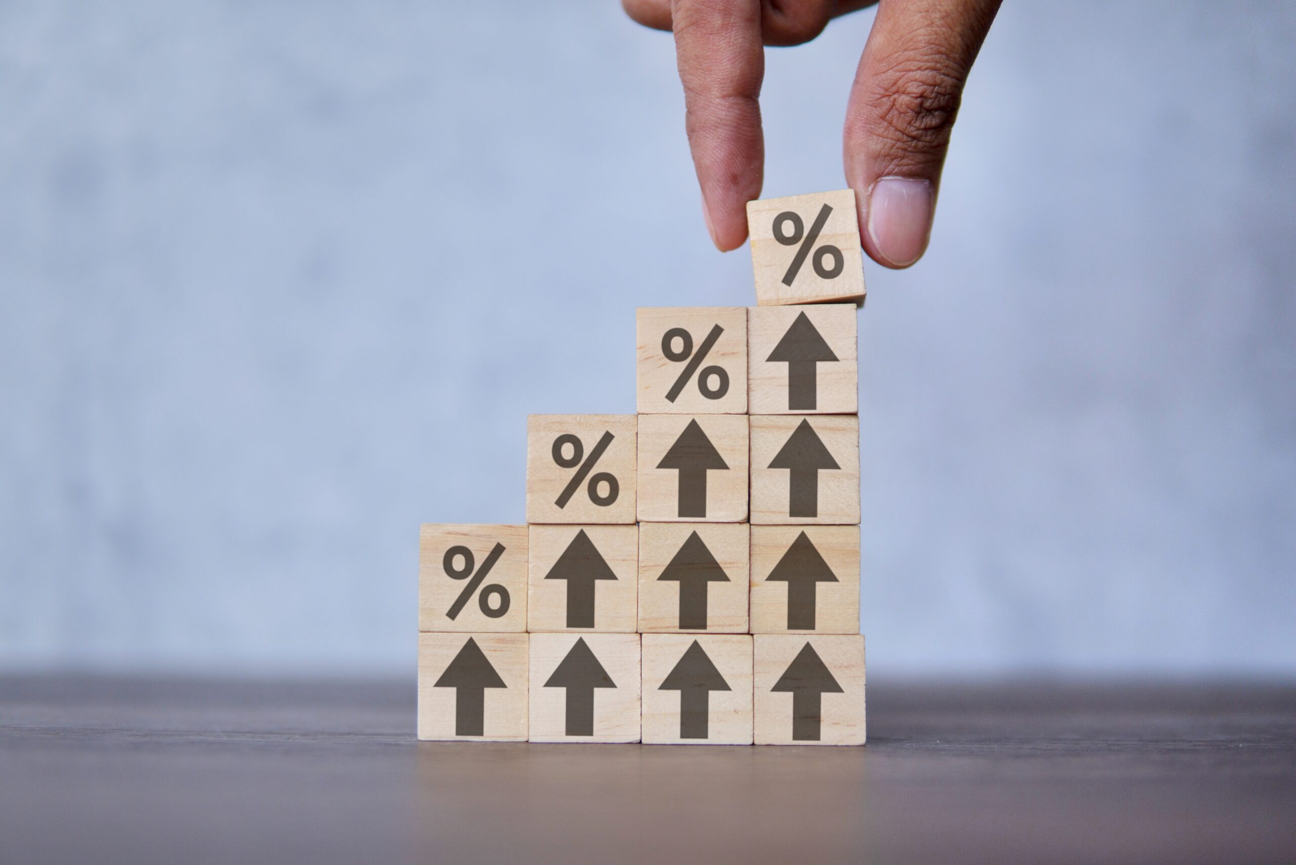 Interest rate, growth and business concept. Hand putting wooden cube block with icon percentage on top of arrow upward direction.